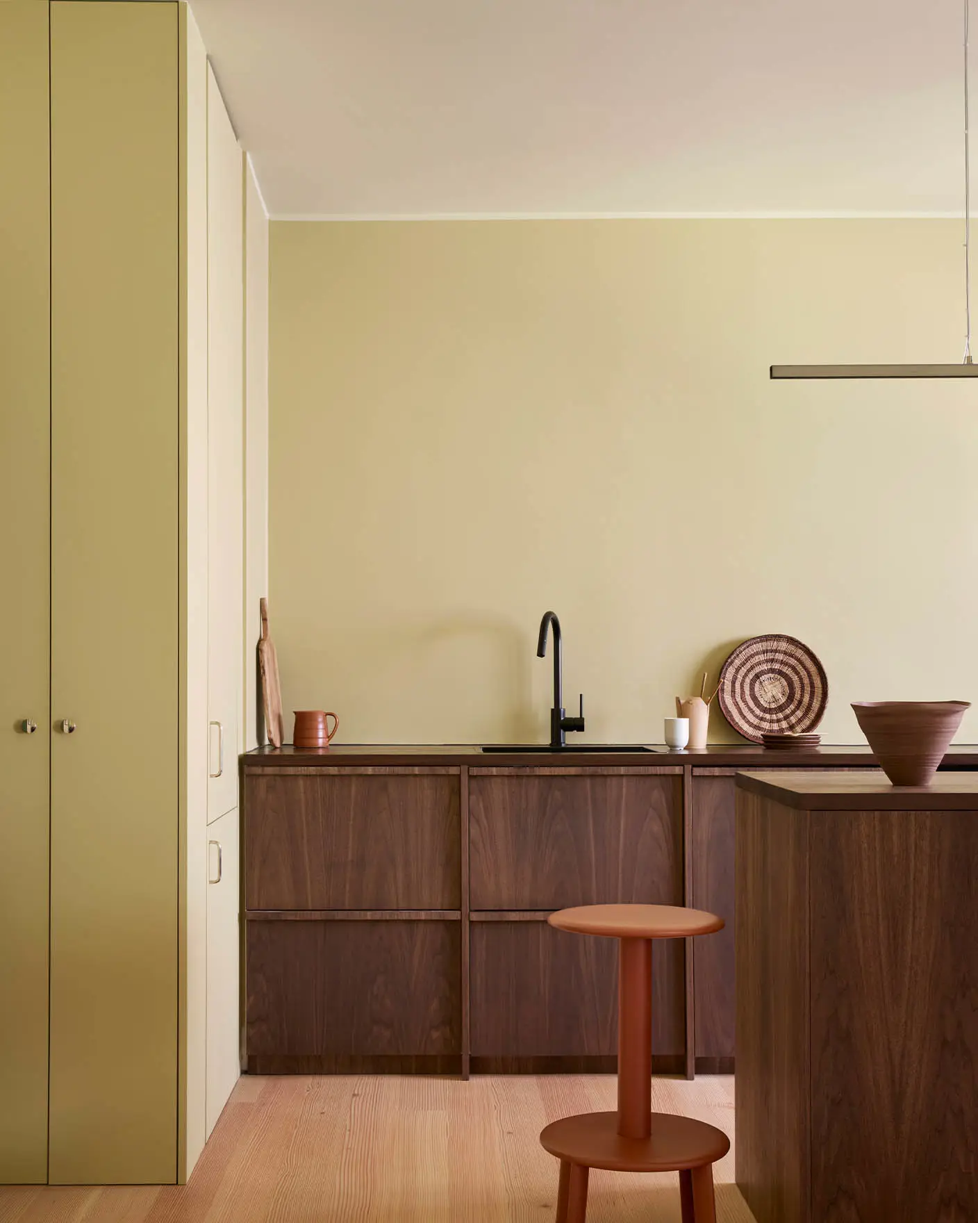 Kjøkkenveggene er malt i Jotun Earty Yellow, med skap i mørk massiv valnøtt