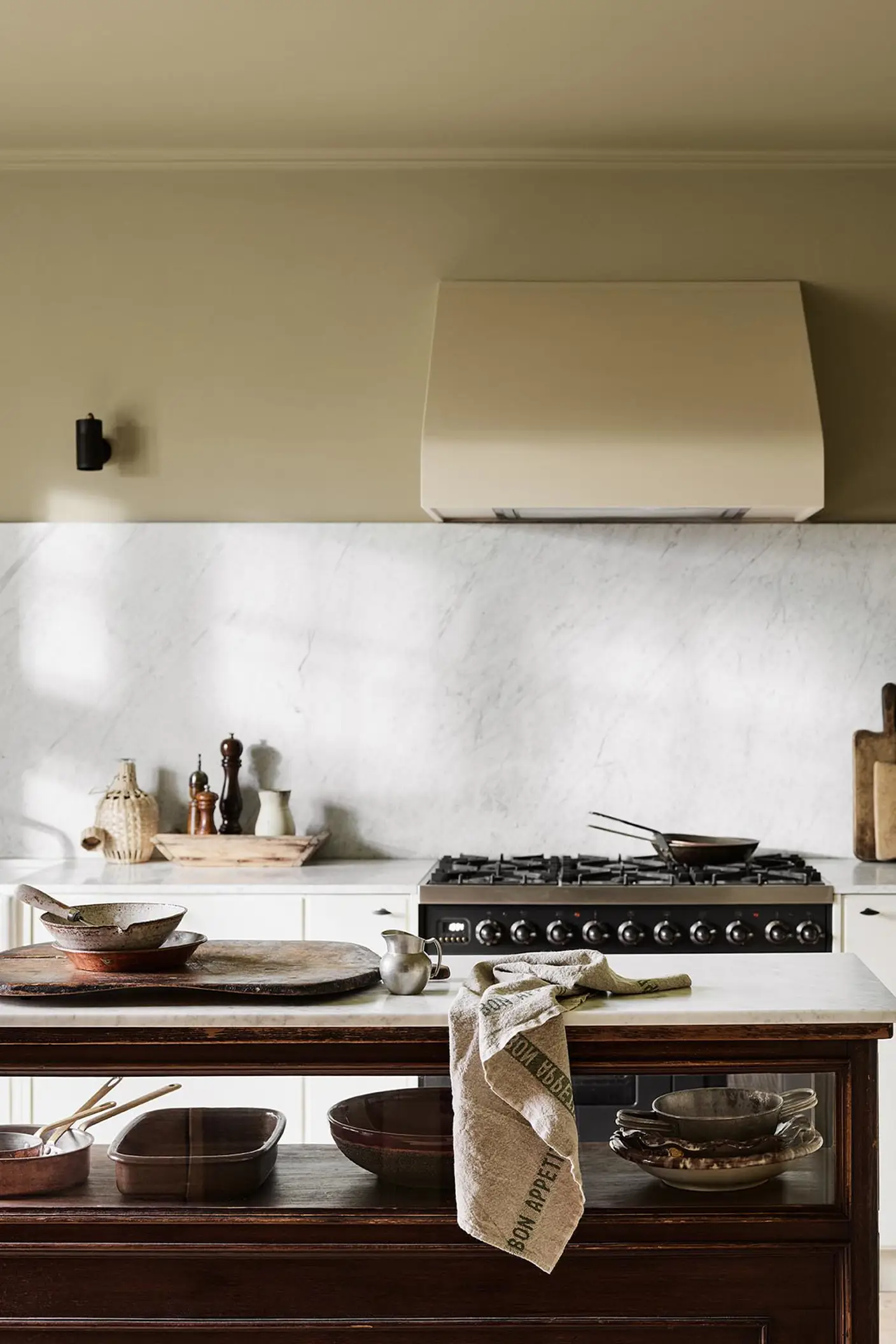 Kitchen with a marble backsplash, white cabinets, and a wooden island. Wall painted with the Jotun colour 8284 Olive.