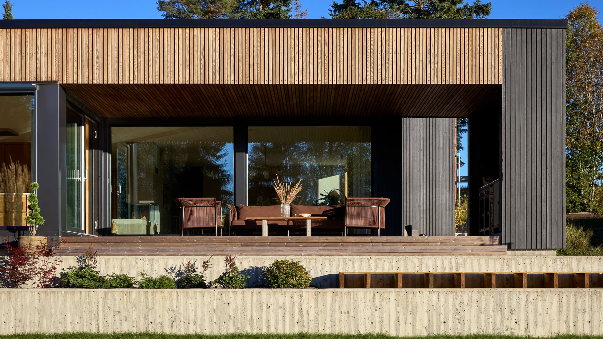 Terrasse med betong, ubehandlet tre og vegger malt sorte i JOTUN 9938 Dempet Sort med DRYGOLIN Nordic Extreme Supermatt.