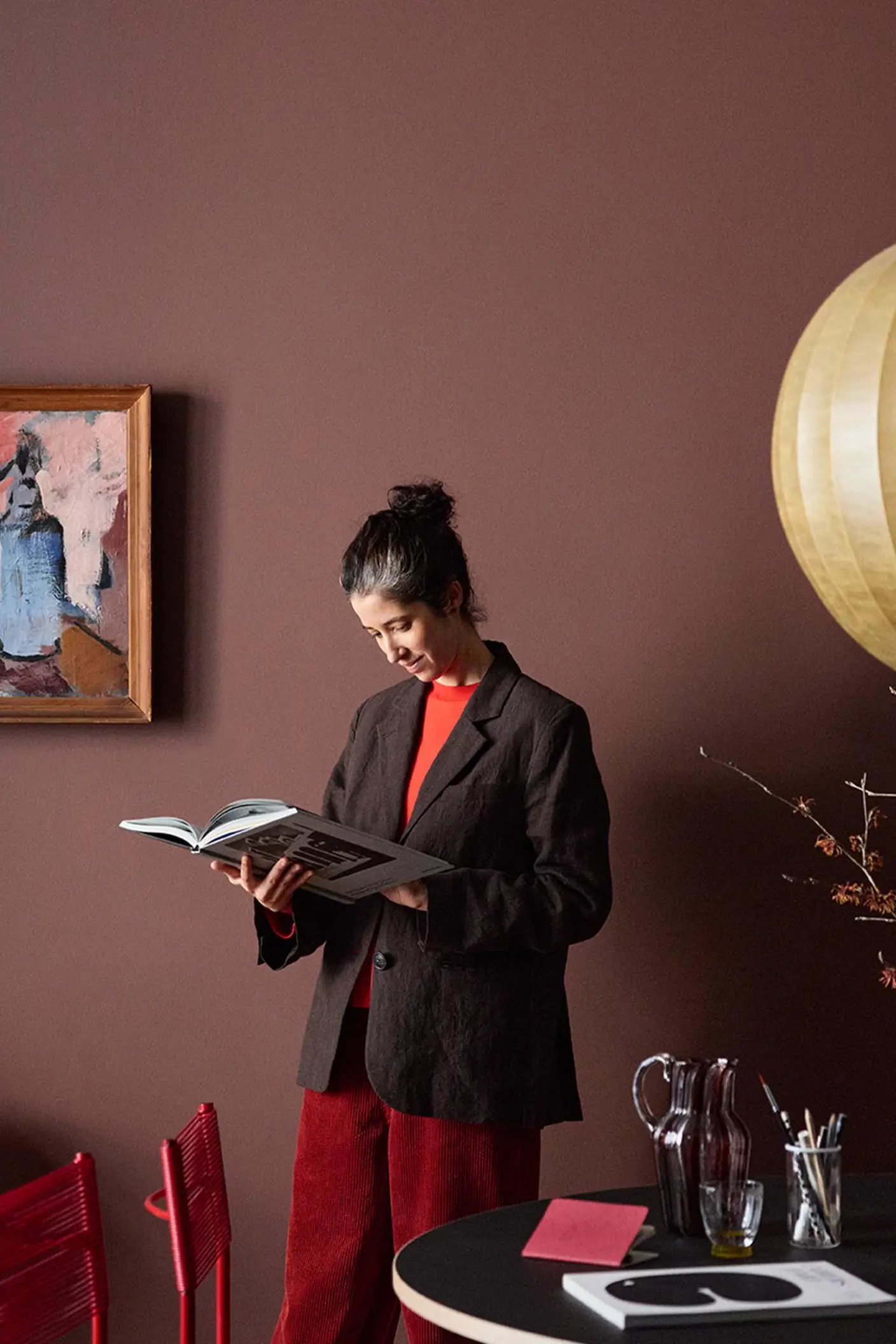 Woman standing reading in front of a deep red wall painted with Jotuns colour 2951 Sophisticated Red.