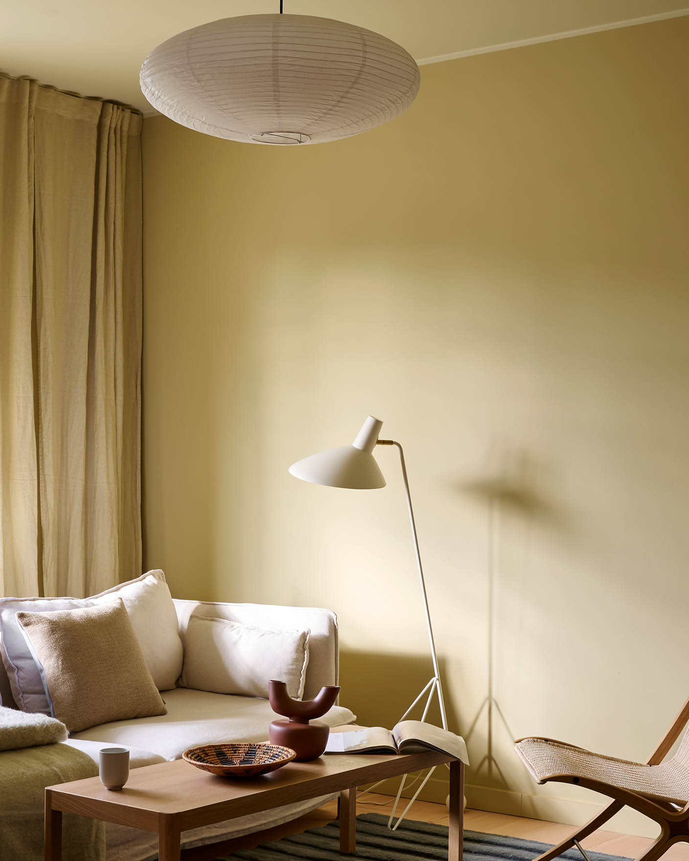 Lys stue med vegger i Jotun Humble Yellow, hvit sofa, beige gardiner og tak malt i Malmø