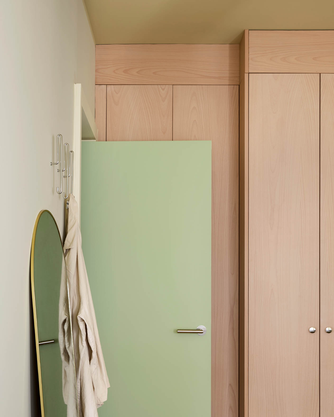Dør i fargen Avocado Green foran høye skap i lyst tre. Veggene er malt i Jotun Malmø, og taket i Earthy Yellow. 
