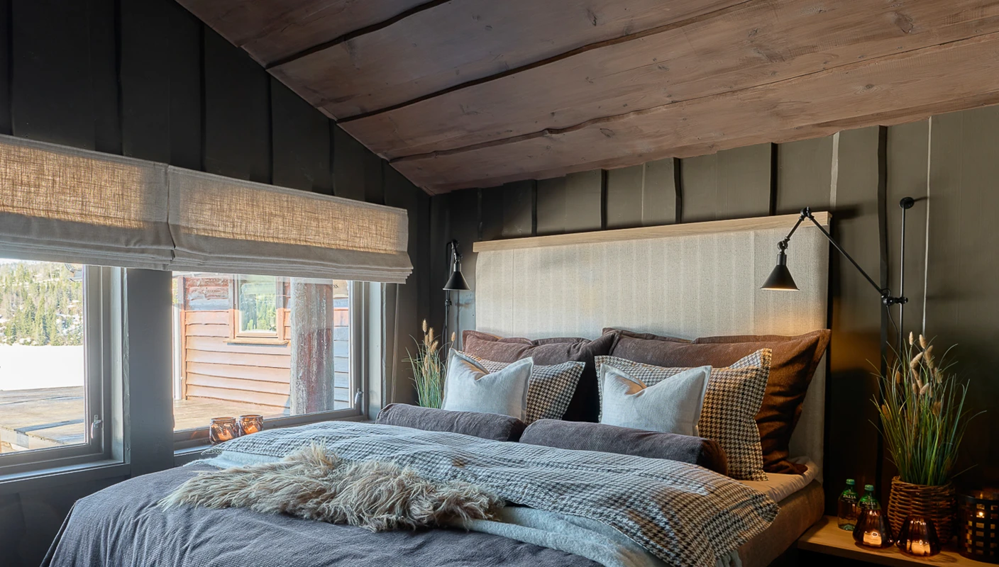 Soverom på hytte med mørk og lun hyttestemning, villmarkspanel på vegg malt i mørkegrå Jotun Evening Stone, tak beiset i jotun Mocca.
