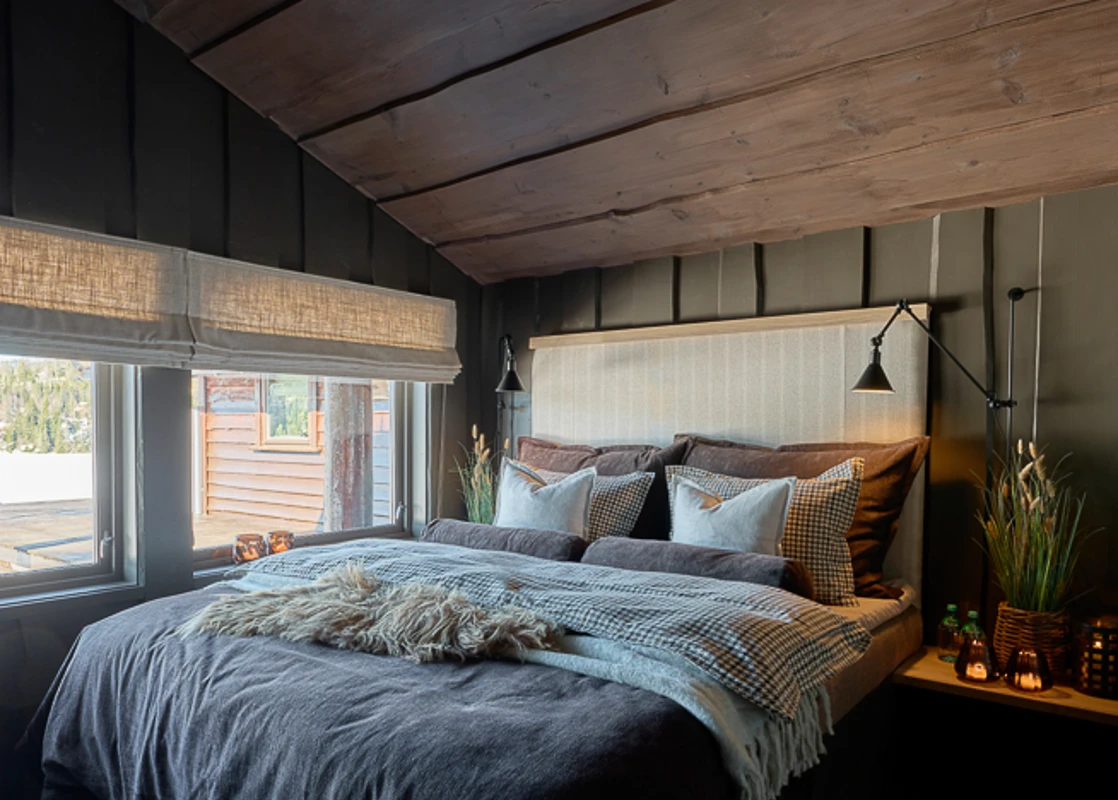 Soverom på hytte med mørk og lun hyttestemning, villmarkspanel på vegg malt i mørkegrå Jotun Evening Stone, tak beiset i jotun Mocca.