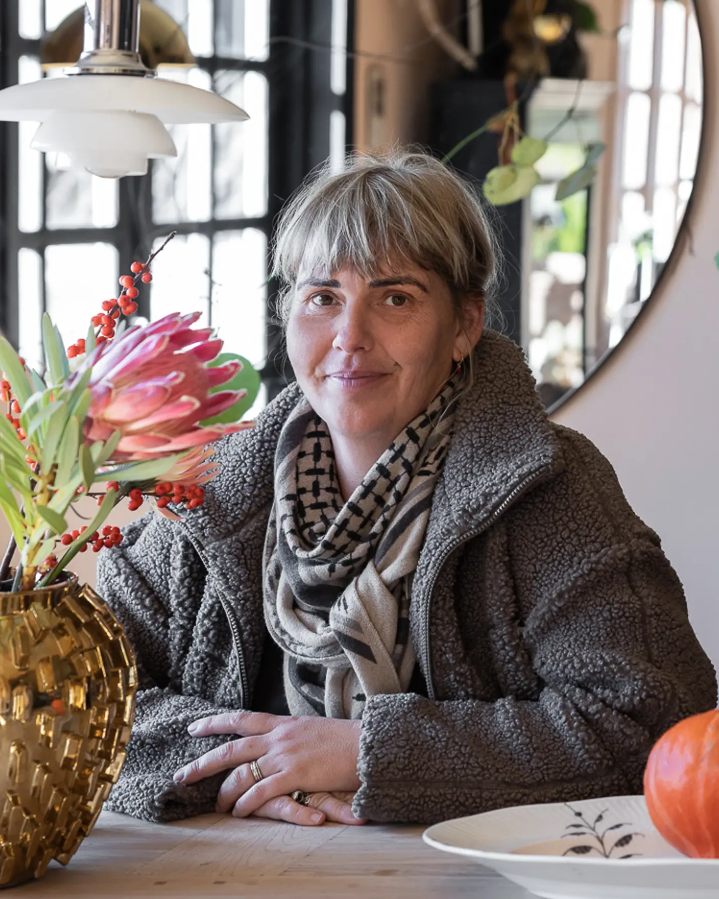 Portrett av Jane Ruby Krucov Jensen ved spisebordet i sin rosa stue malt i Jotun Pink Ambience