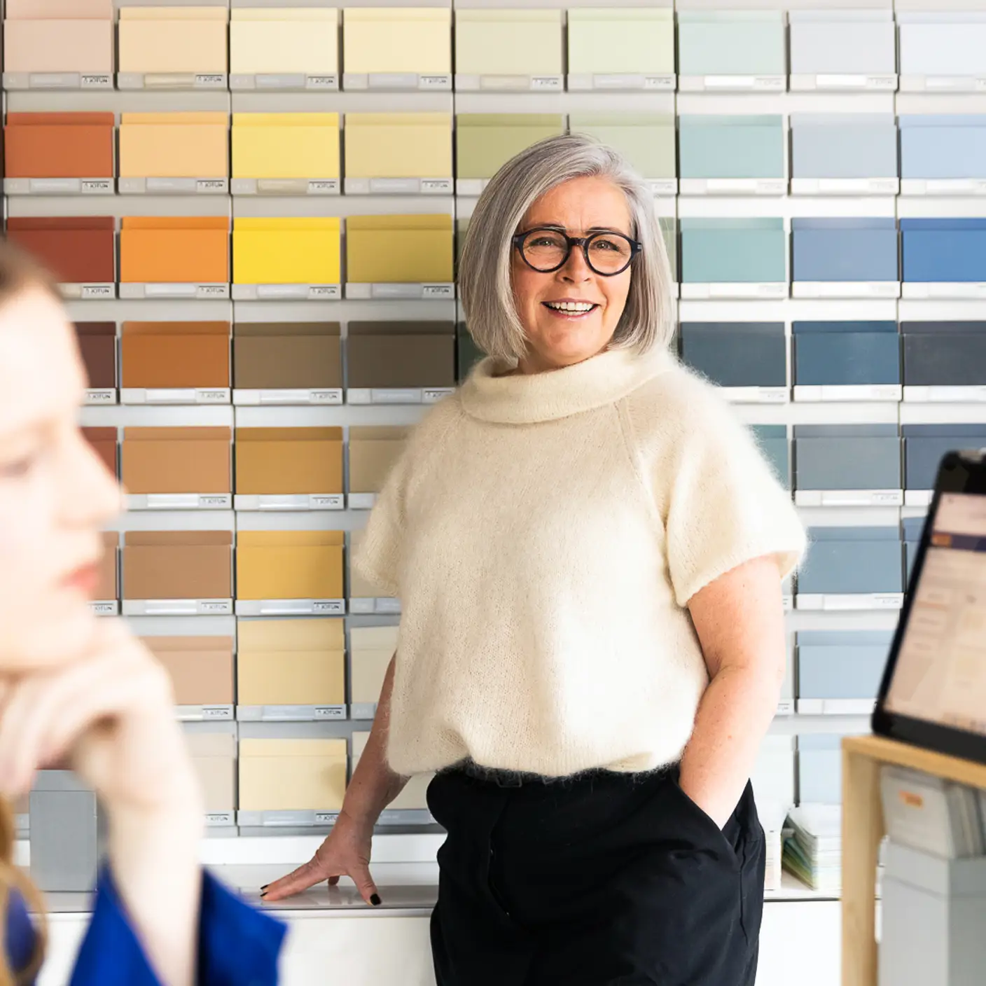 Smilende fargerådgiver foran en vegg med farelameller fra Jotun