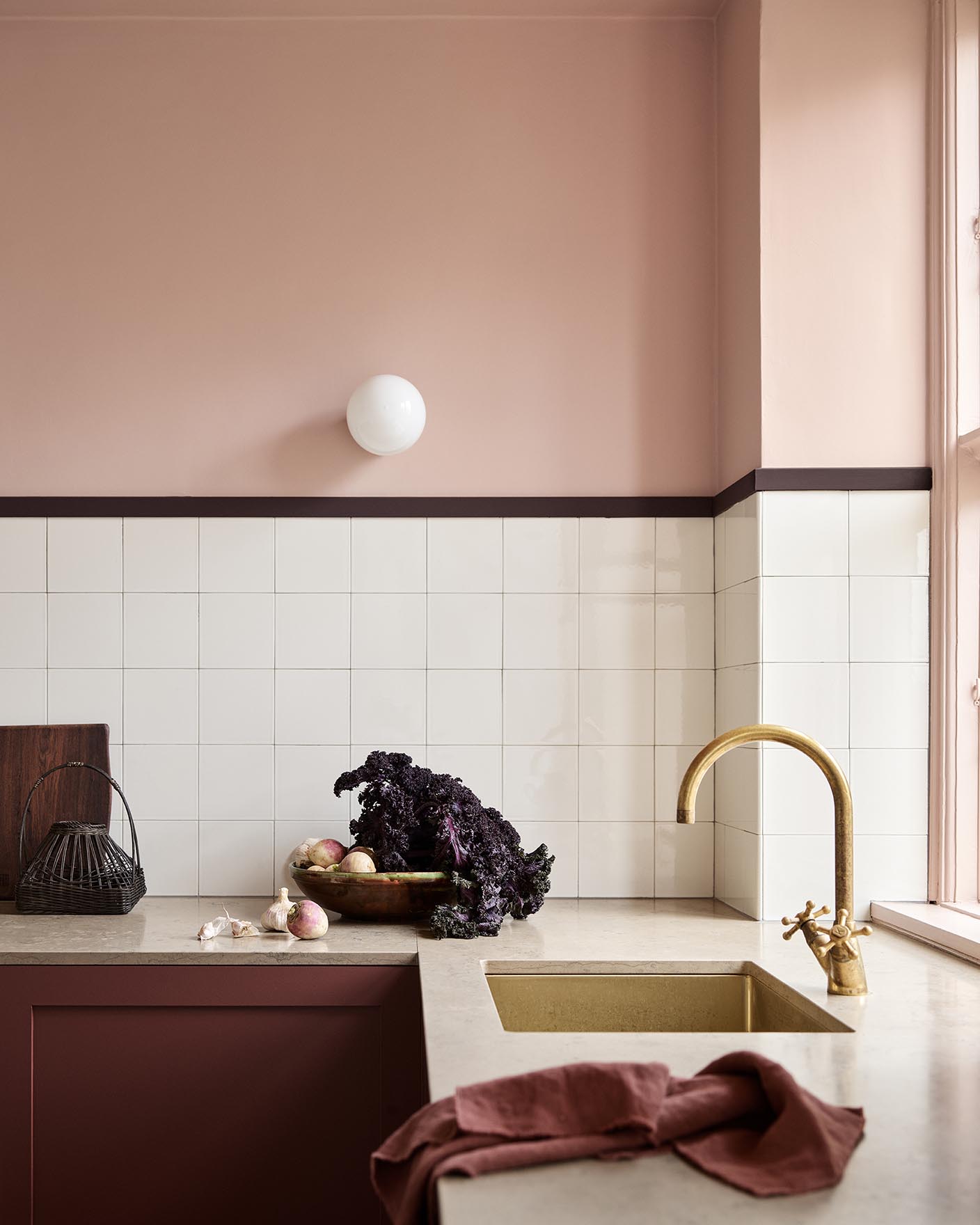 Kitchen counter with vegetables and decor against soft pink walls painted in the colour 20362 Pink Ambience from Jotun and white tile backsplash.