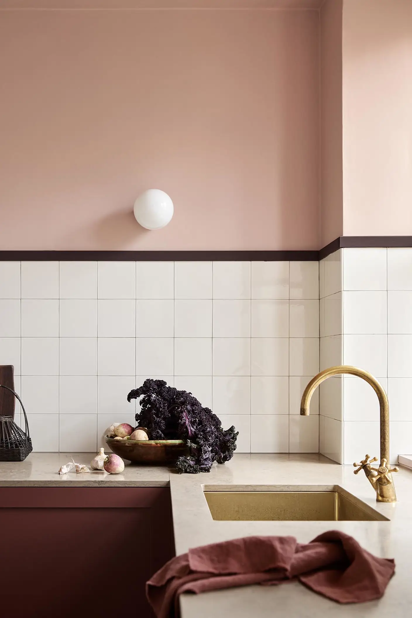 Kitchen counter with vegetables and decor against soft pink walls painted in the colour 20362 Pink Ambience from Jotun and white tile backsplash.