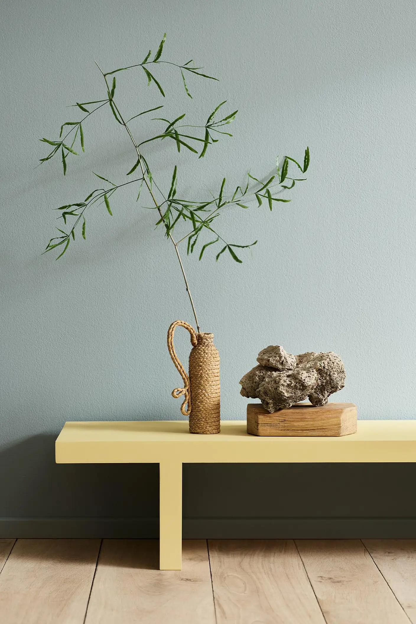 Minimalist interior with a greenish yellow bench in the colour 1965 Ginger Tea set against a muted blue wall painted with 6378 Iconic from Jotun.