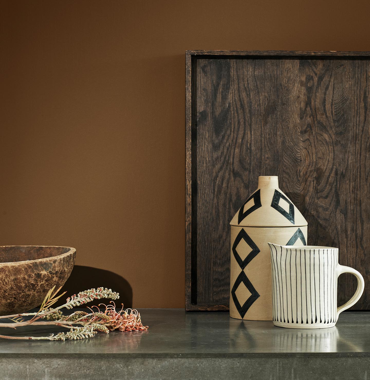 Rustikke elementer i lys  keramikk, detaljer i tre foran vegg malt i gyllenbrune Jotun 12127 Earthy Brown