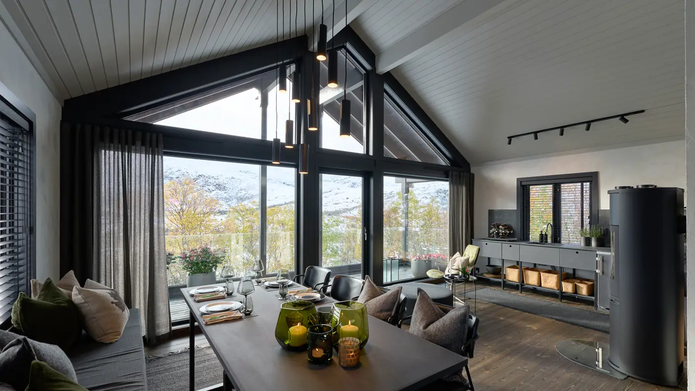 Utsikt gjennom nye store vinduer over hele endeveggen i hytte.