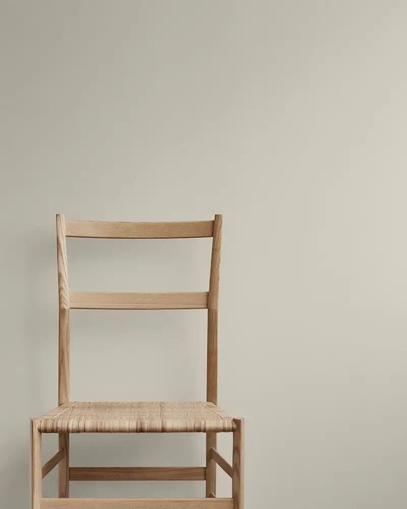 Minimalistisk trestol med flettet sete mot lys vegg malt i fargen Sheer grey, skandinavisk interiørdesign.