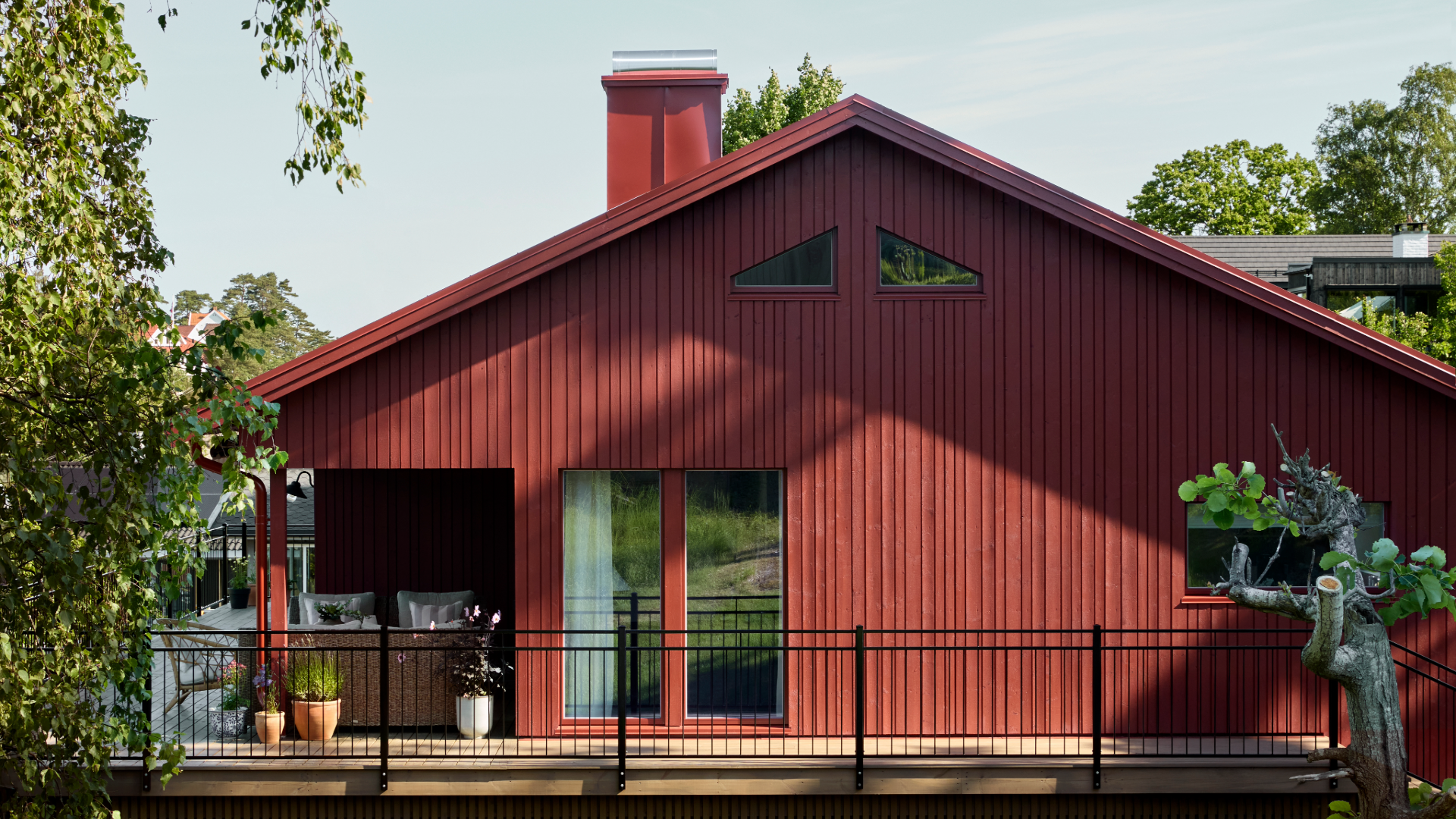 Moderne hus malt i Jotun Villvin, svart smijernsrekkverk foran en luftig terrasse.