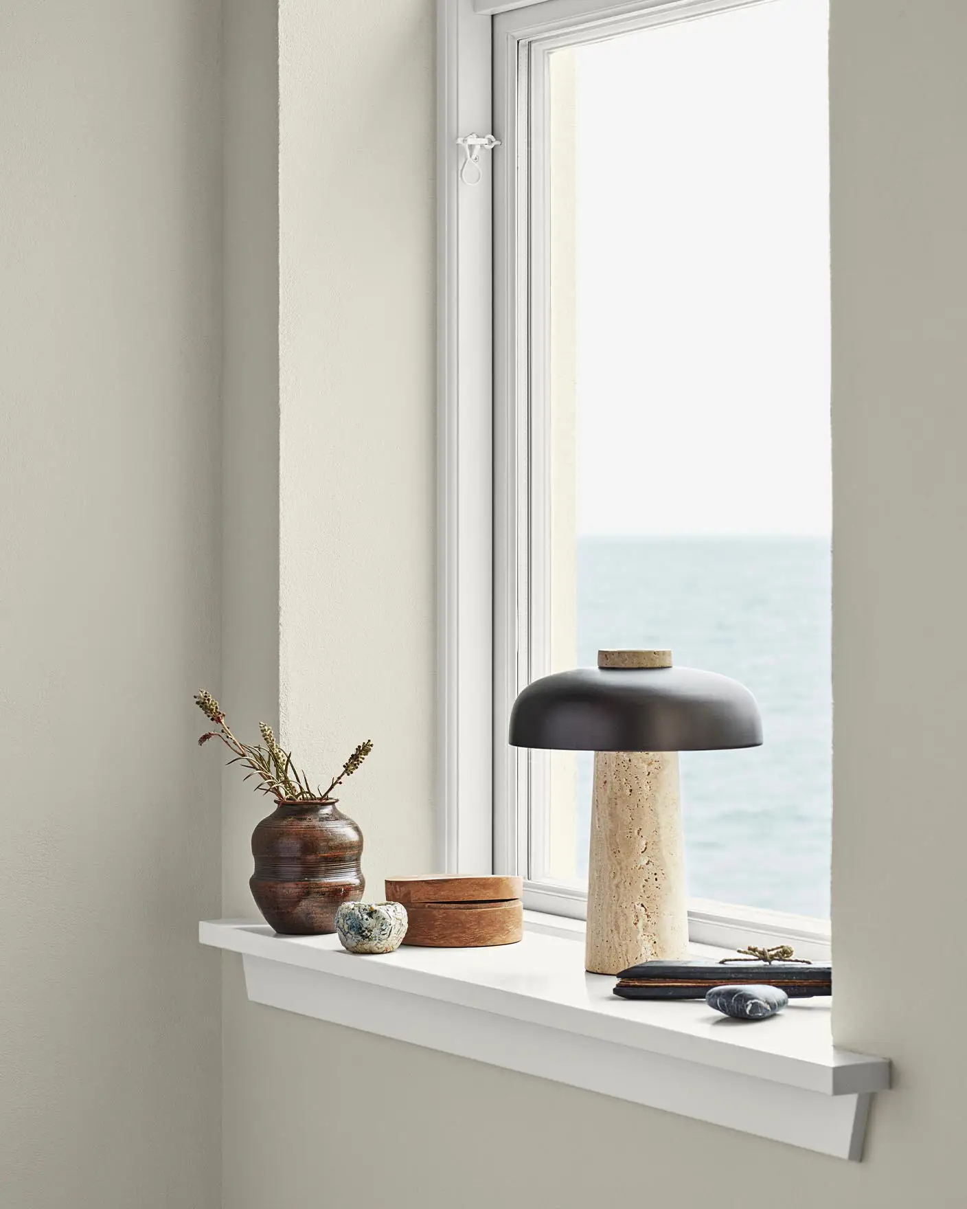 Mjukt beige väggar målade i Jotun 1024 Tidlös ramar in en havsutsikt. Klara vita lister målade i Jotun 9918 Klassisk Vit.