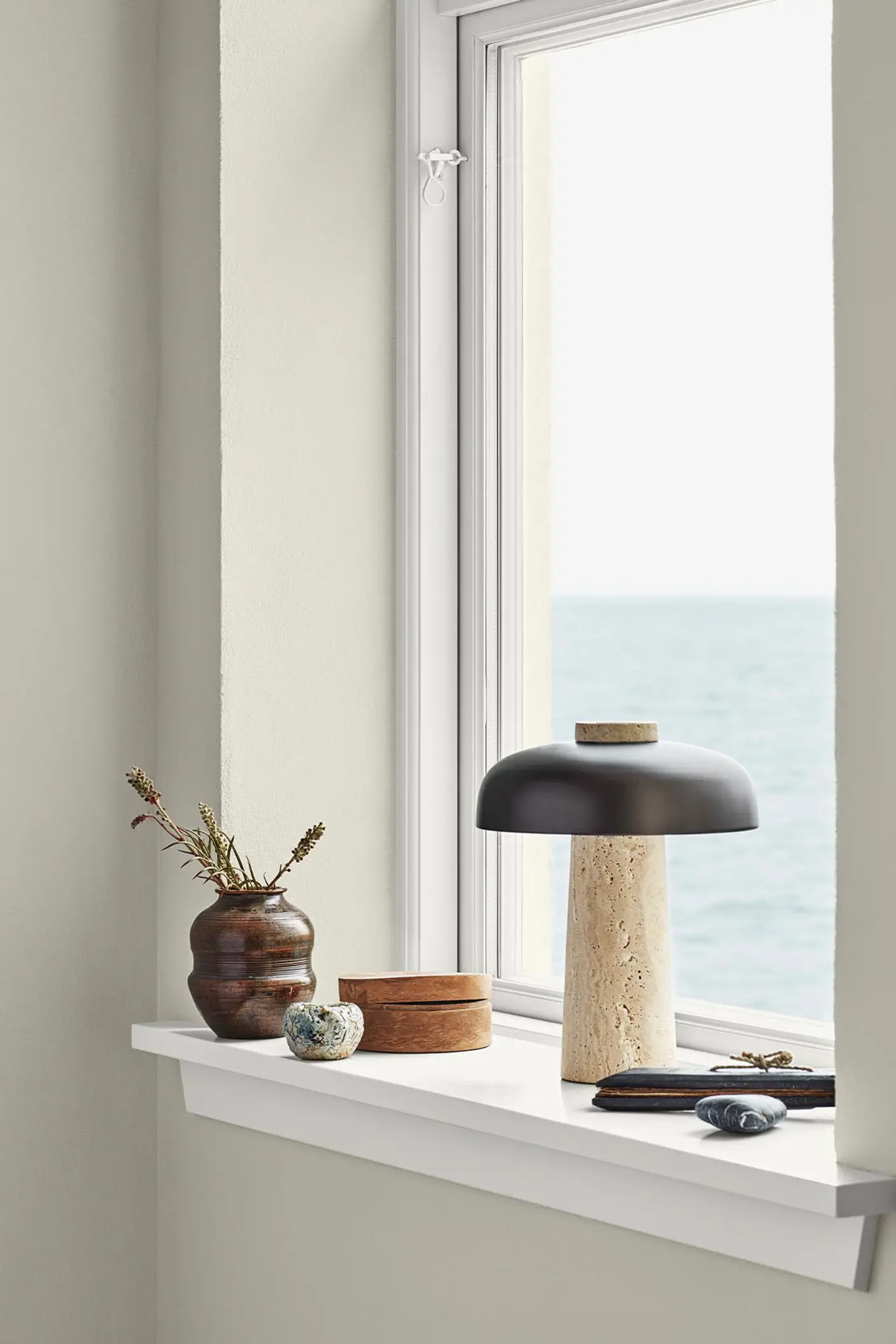 Paredes beige suaves pintadas con Jotun 1024 Timeless enmarcan una vista al océano. Molduras blancas puras pintadas con Jotun 9918 Classic White.