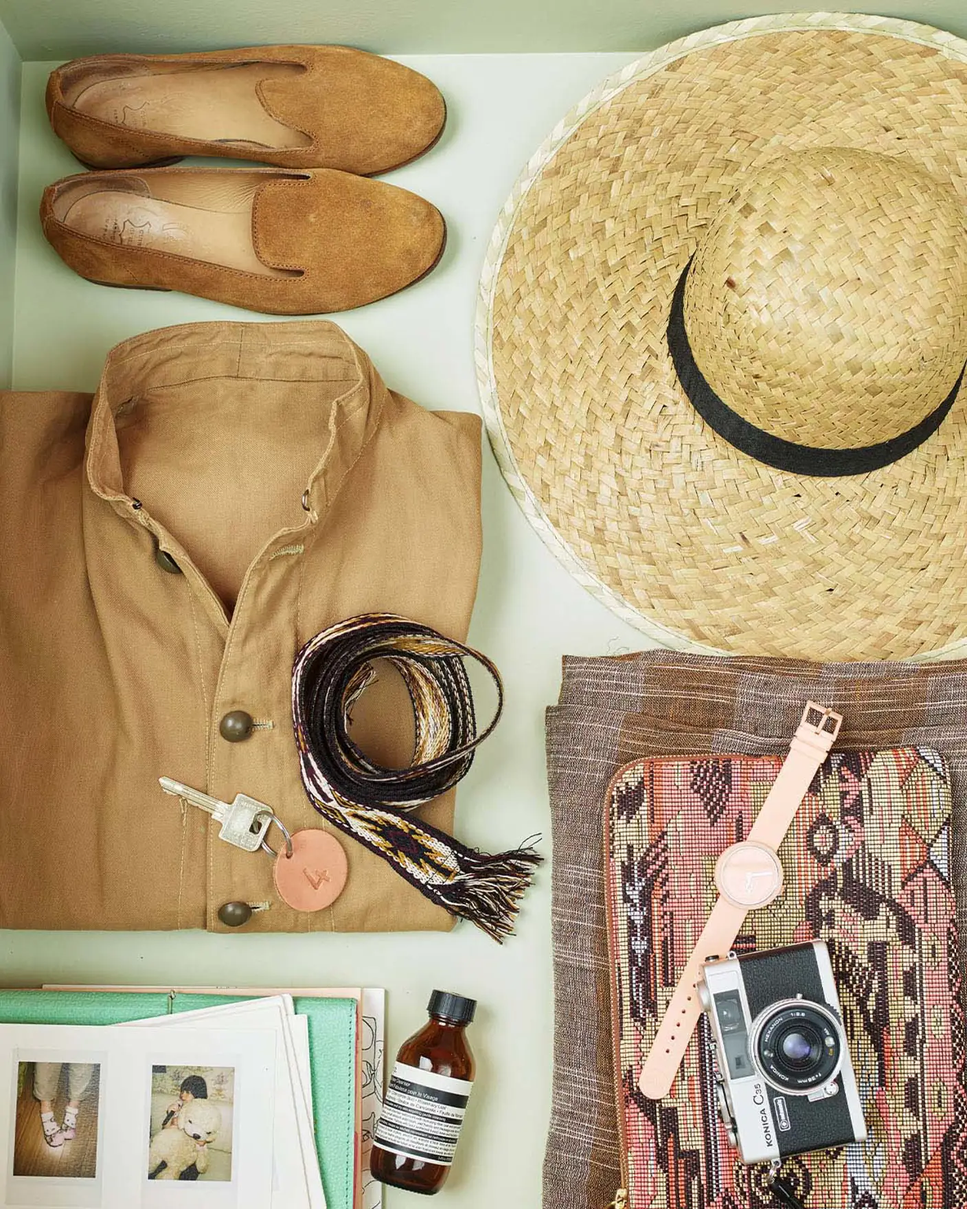 Et par sko, stråhatt, brettet skjorte, vevd belte, vintage kamera og personlige tilbehør, pent ordnet i en skuff malt med 8222 Jurrasic Grey, en gulgrønn farge fra Jotun.