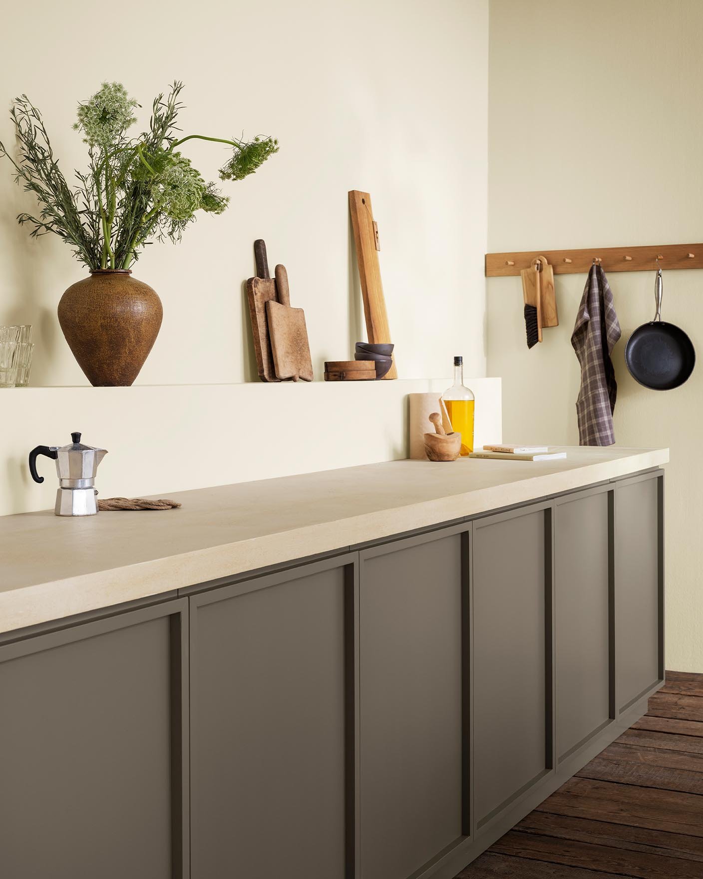 This kitchen feels airy and grounded with its golden beige walls painted by Jotun 1276 Soft and golden brown cabinets in the colour 11012 Rustic Brown from Jotun.