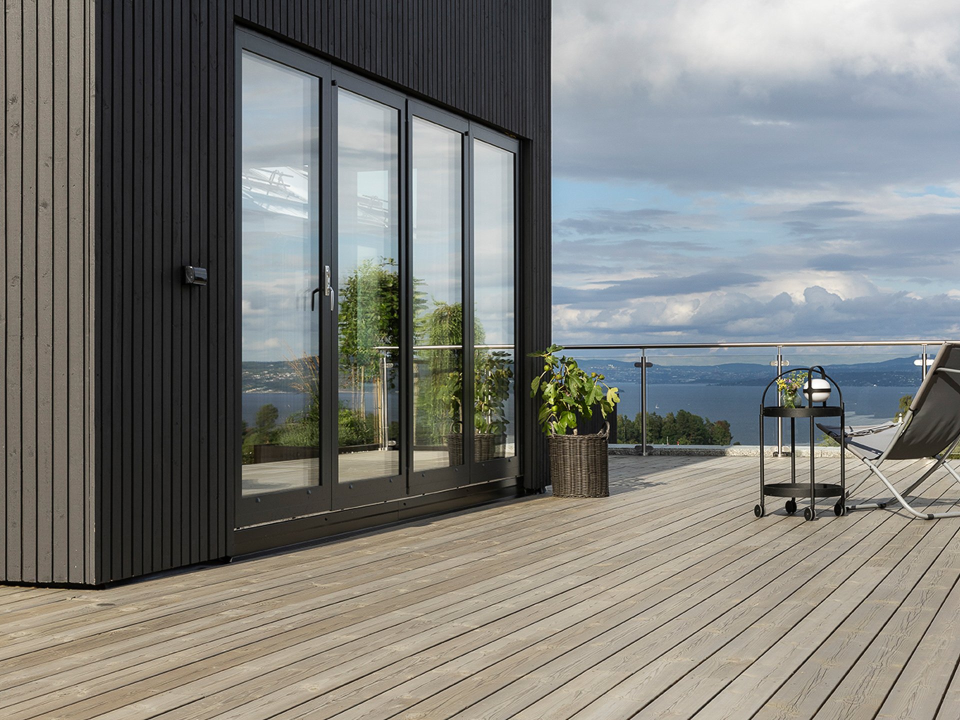 Husfasade malt i Jotun Dempet Sort med terrasse beiset i TREBITT Naturlig Sølvgrå.