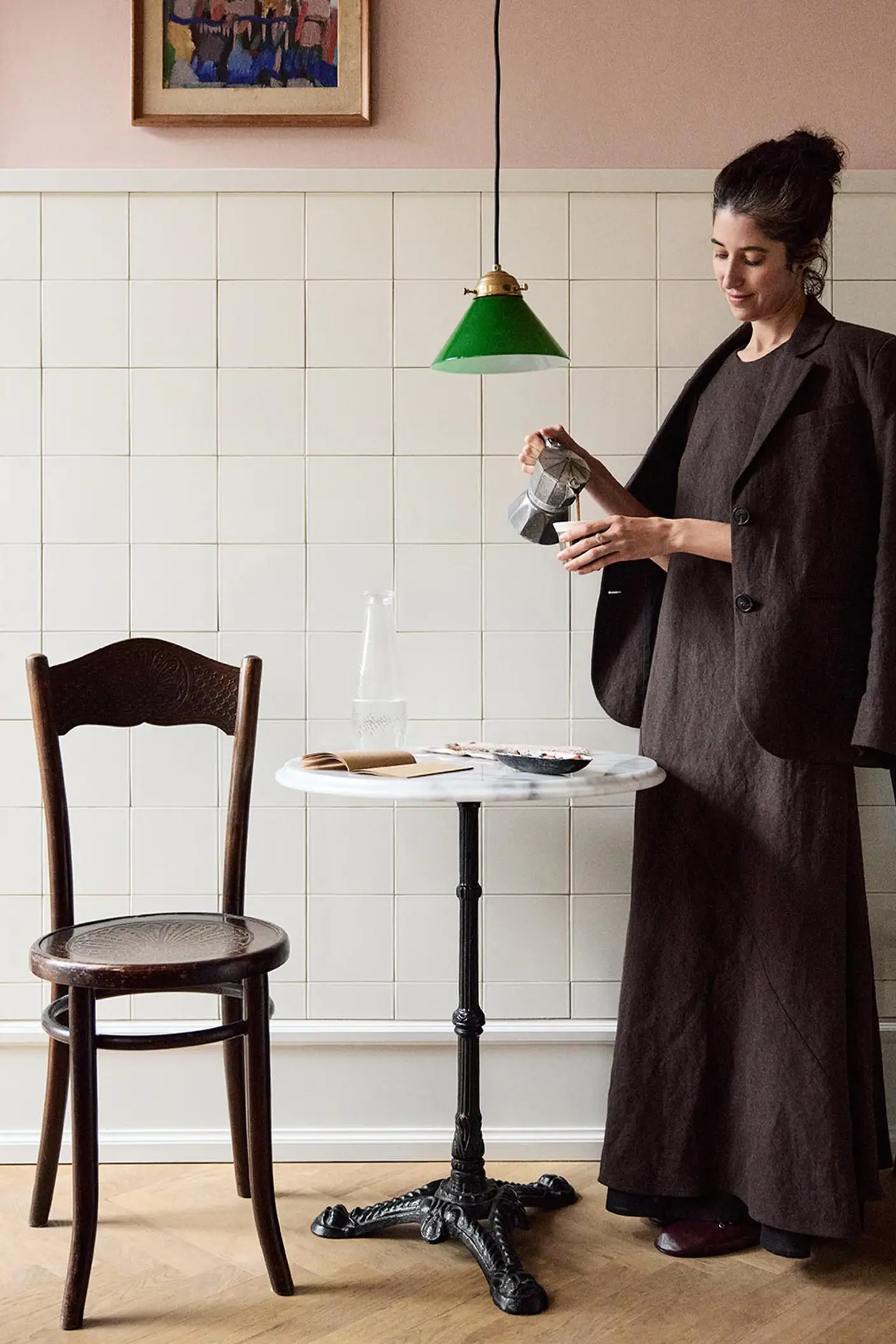 Woman standing in front of a tiled wall. The upper wall is painted in the soft pink colour Jotun 20362 Pink Ambience.