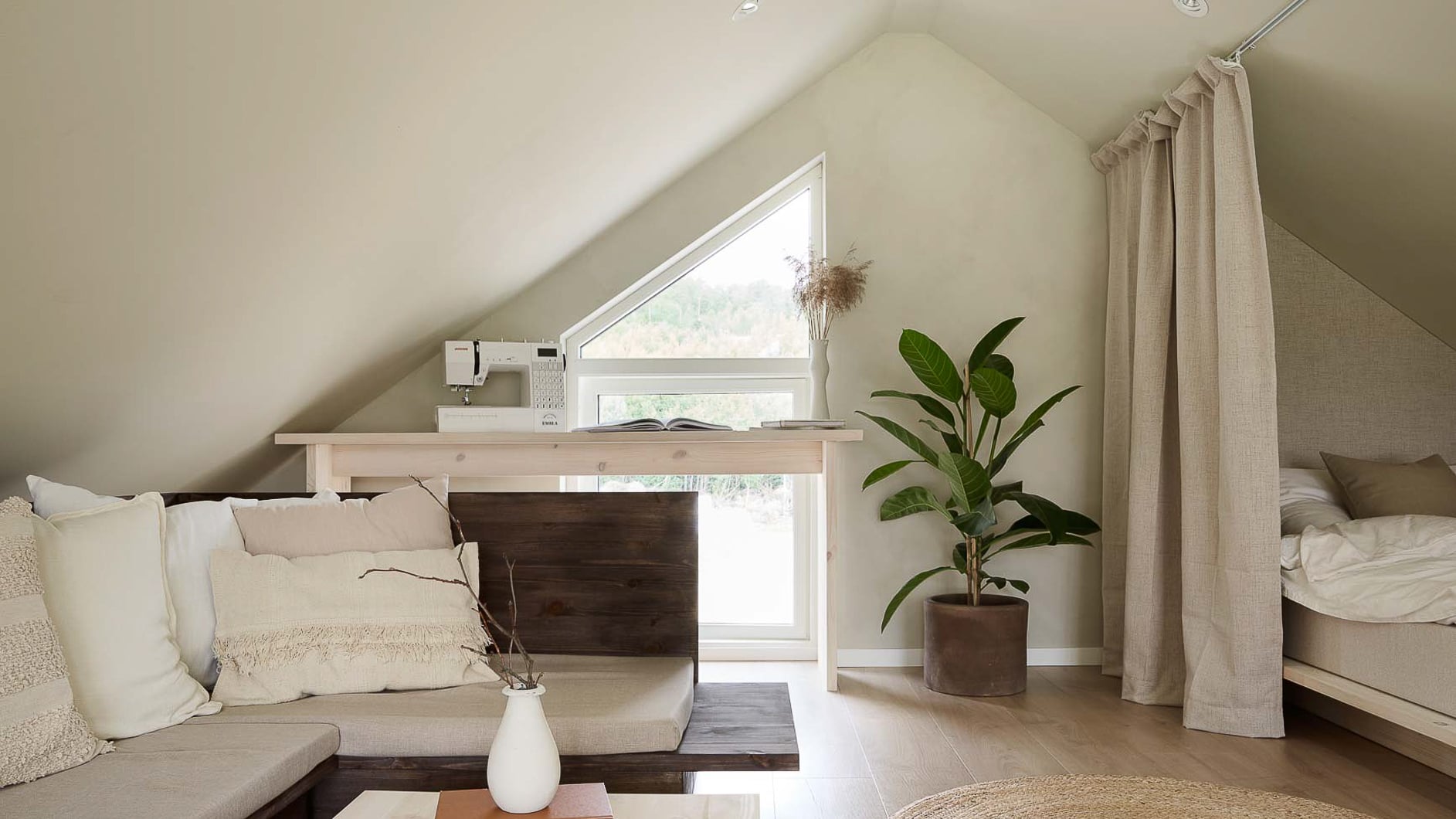 Lyst og minimalistisk loftsoverom med seng, skrivebord, stort vindu og grønn plante, alt malt lyst i fargen Jotun Space.