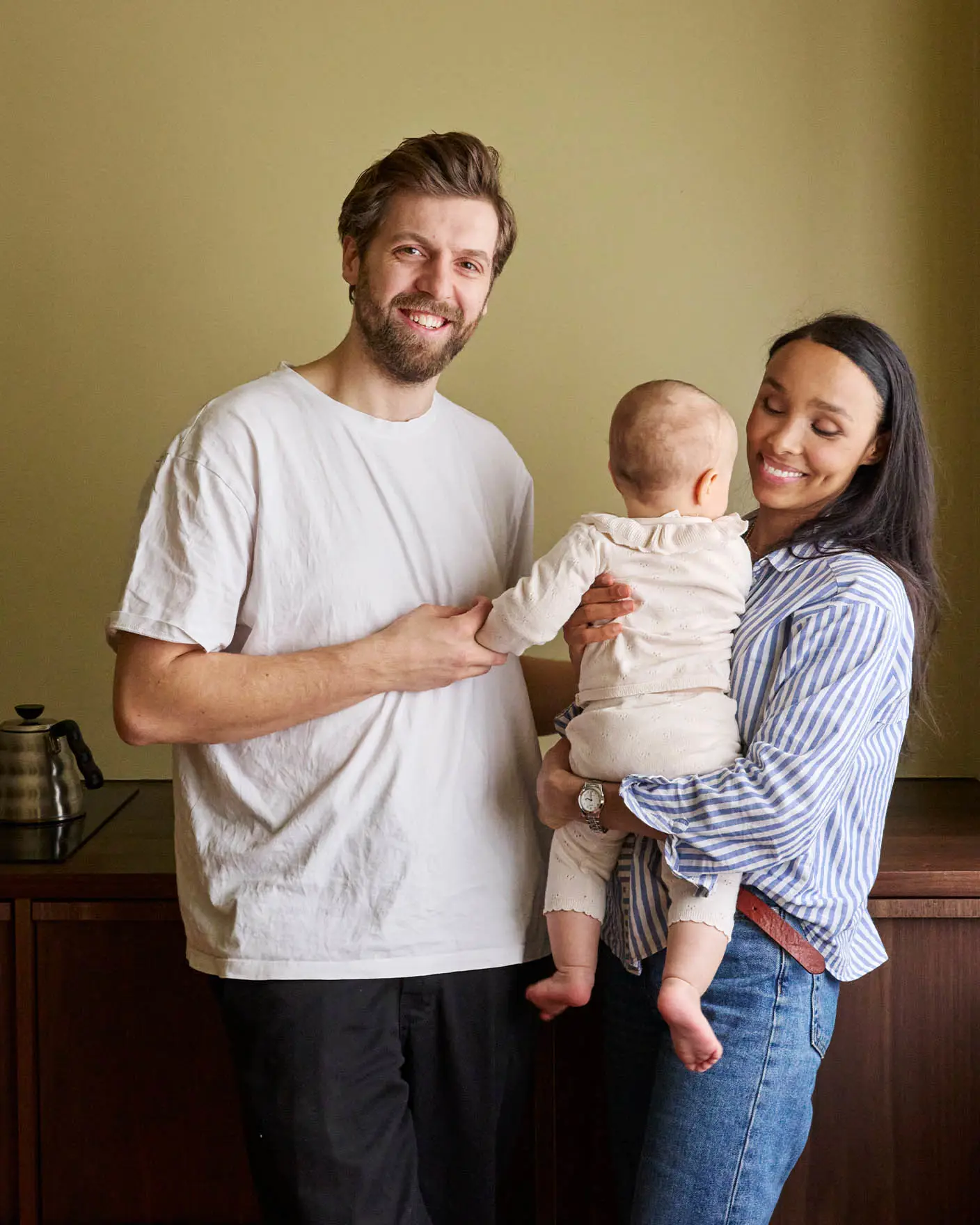 En familie foran en vegg malt med Jotun LADY 8583 Earthy Yellow. En myk beige bakgrunn med varme nyanser som skaper en koselig og innbydende atmosfære