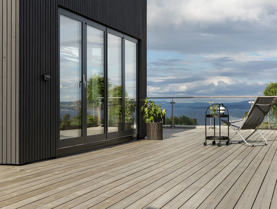 Sort moderne hus malt i Jotun 9938 Dempet Sort, med grå terrasse i TREBITT 90029 Naturlig Sølvgrå.