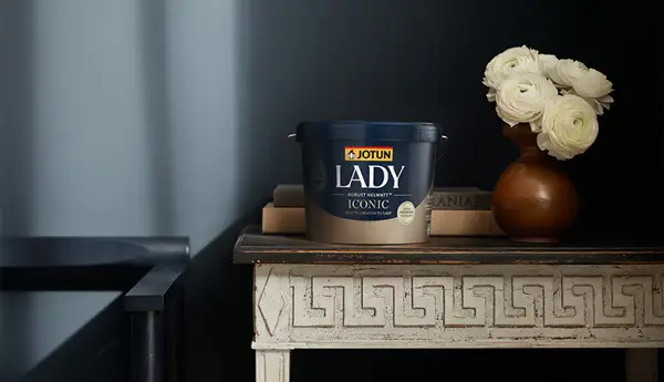JOTUN LADY Iconic malingsspann på et dekorert bord med hvite blomster og bokser i et stilrent interiør.