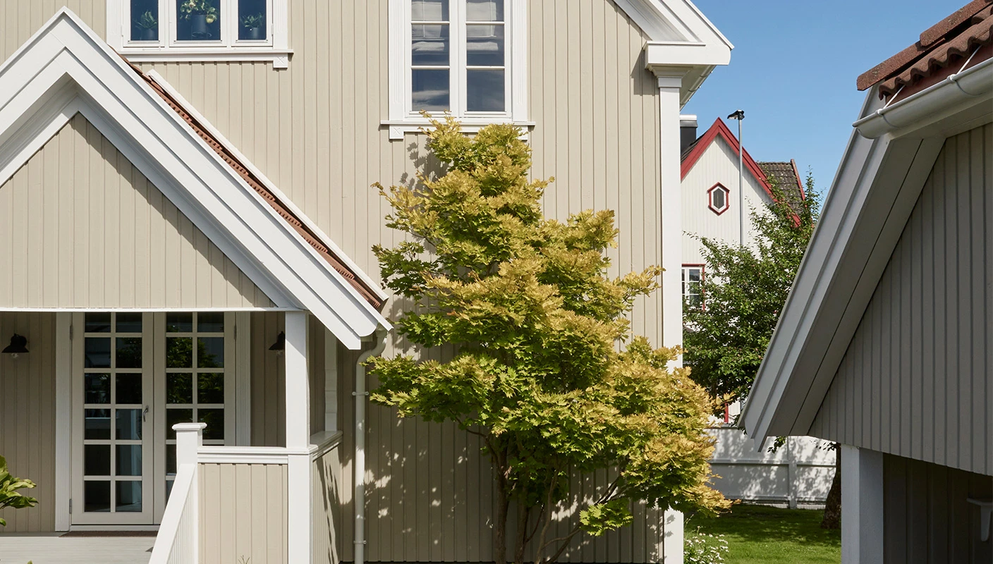 Klassisk villa malt i en mørk beigetone med Jotun Sandbeige og hvite detaljer i Jotun Klassisk Hvit.