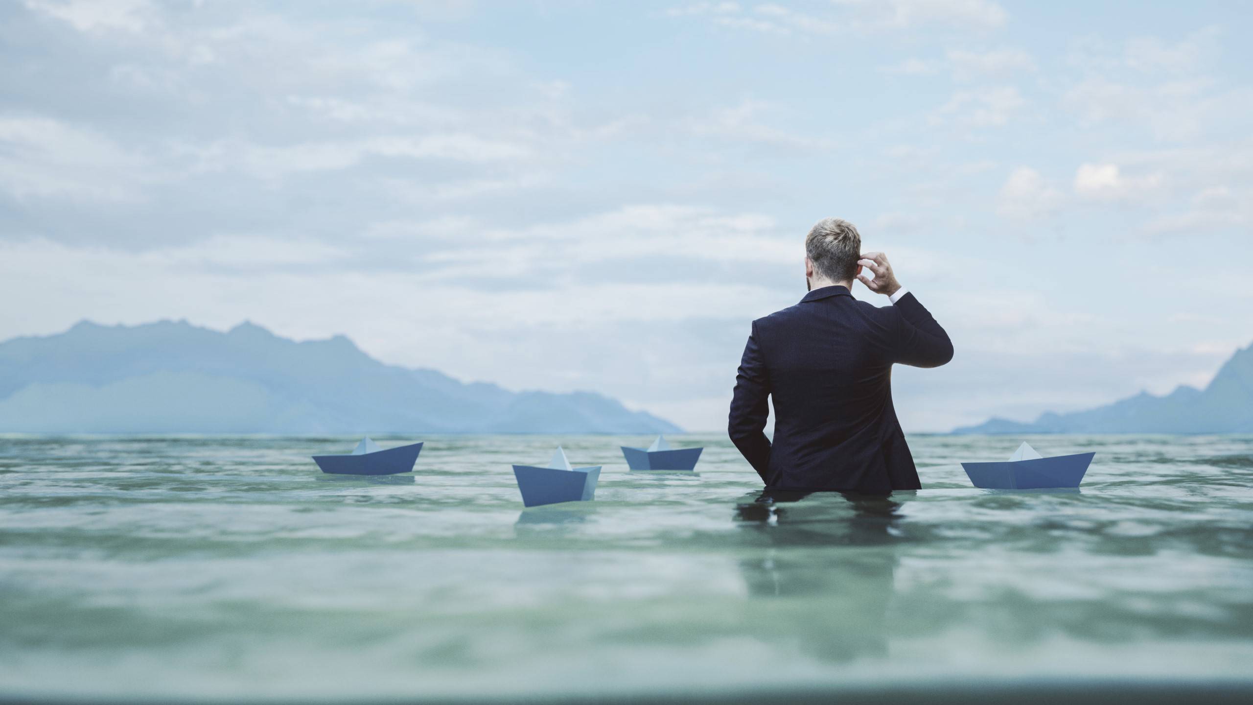 Man wading among paper ships