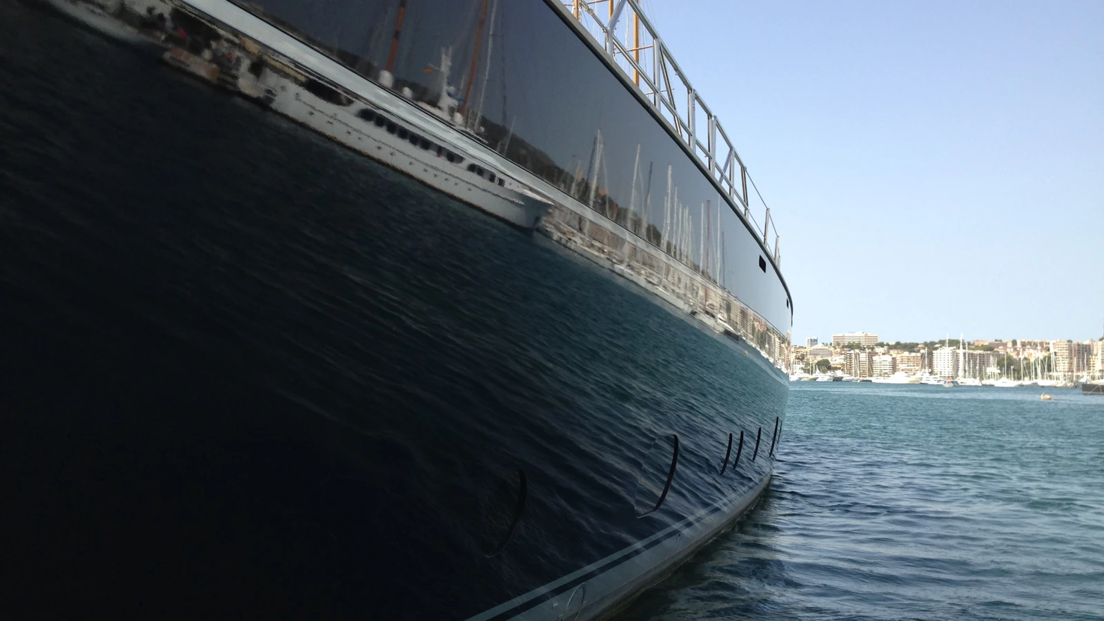 a yacht hull reflected in calm marina waters with sailboats 