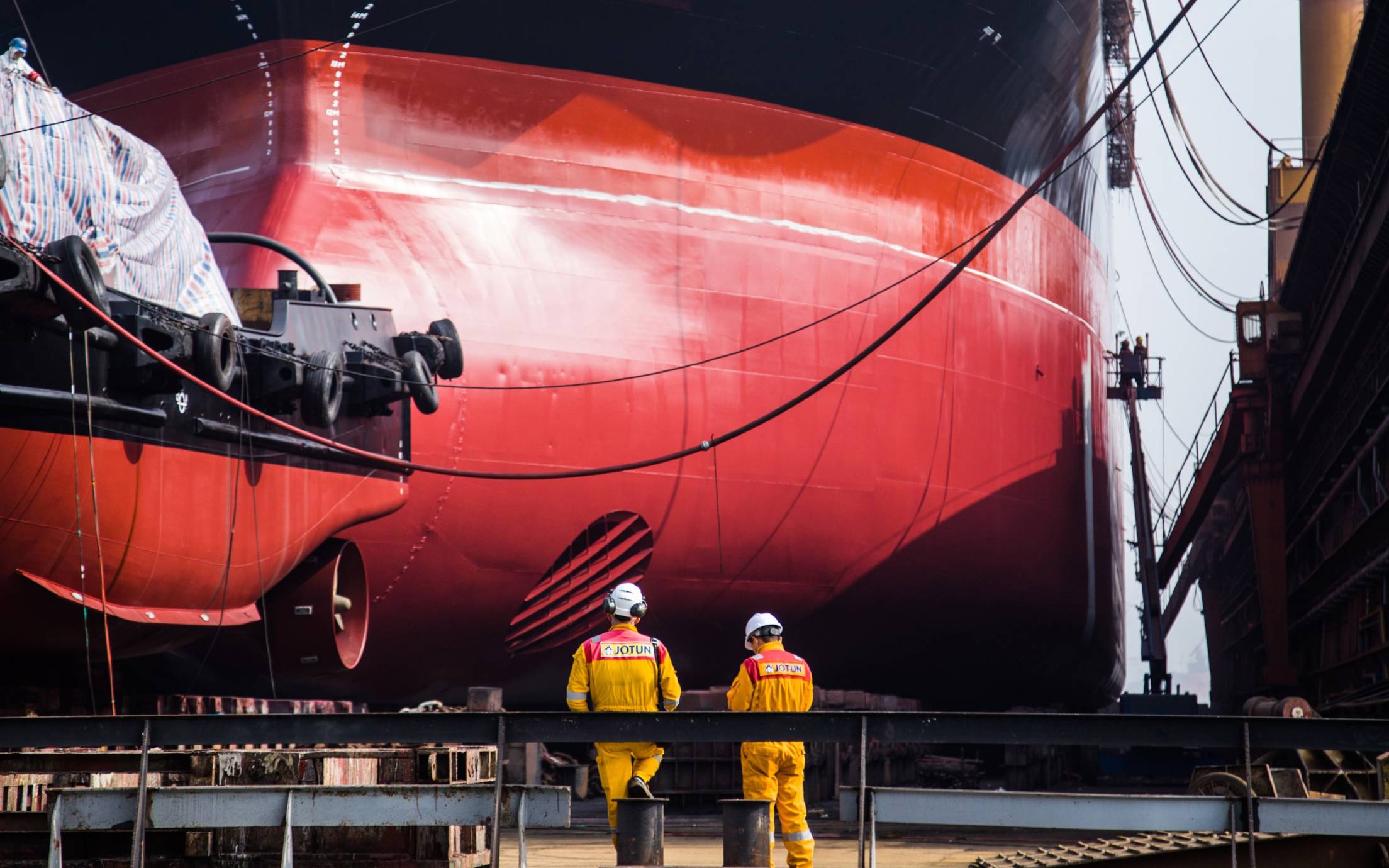 Photo of red painted hull and two workers standing in front