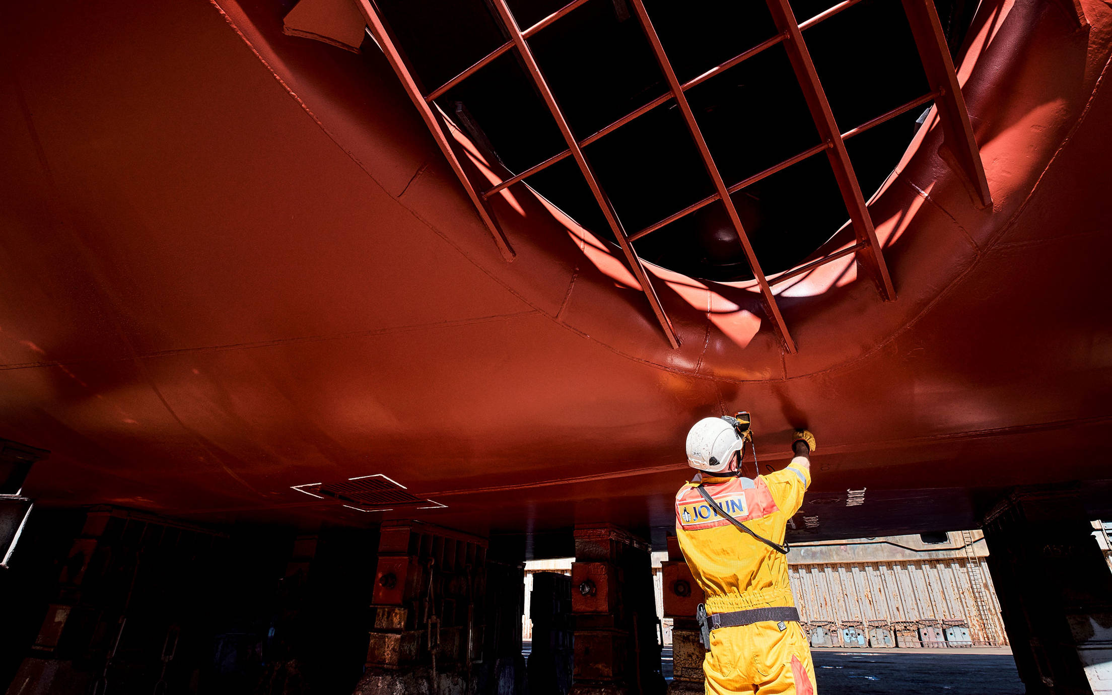 A technical inspector measuring thickness of the coating on a ship hull
