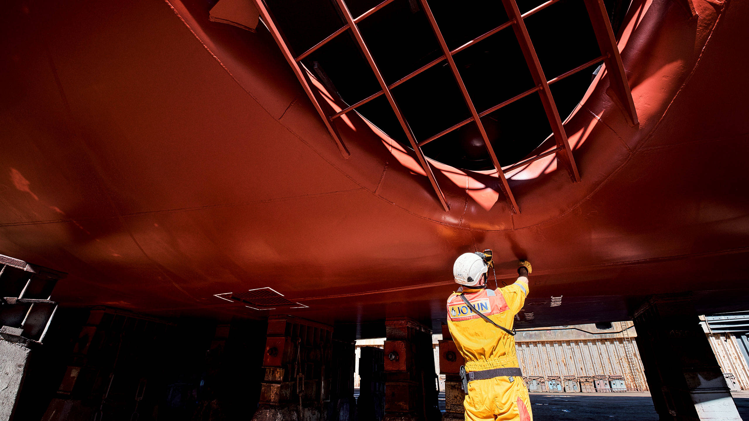 A technical inspector measuring thickness of the coating on a ship hull