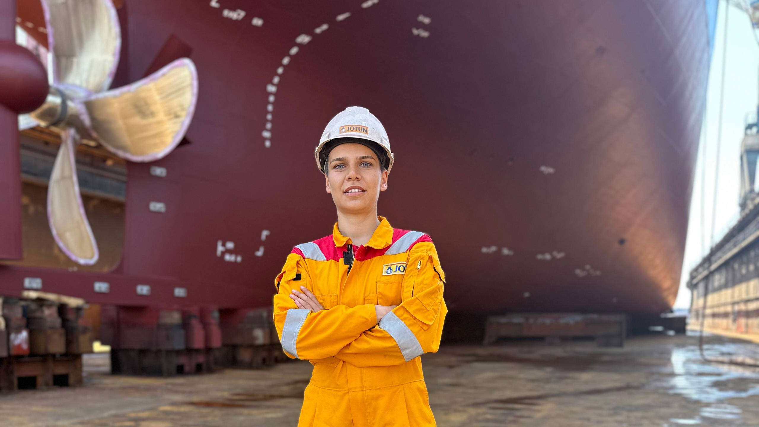Nilay Yilmaz with her arms crossed in front of a ship hull