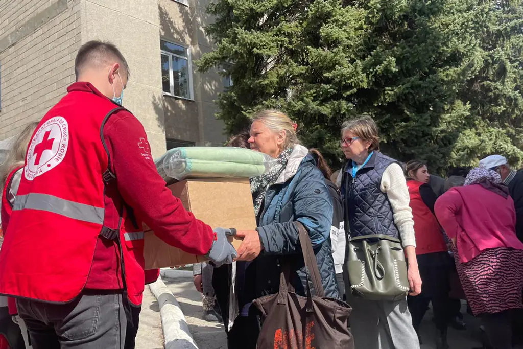 A woman receiving food and blankets from a Red Cross worker. Photo: Ville Palonen / Finnish Red Cross