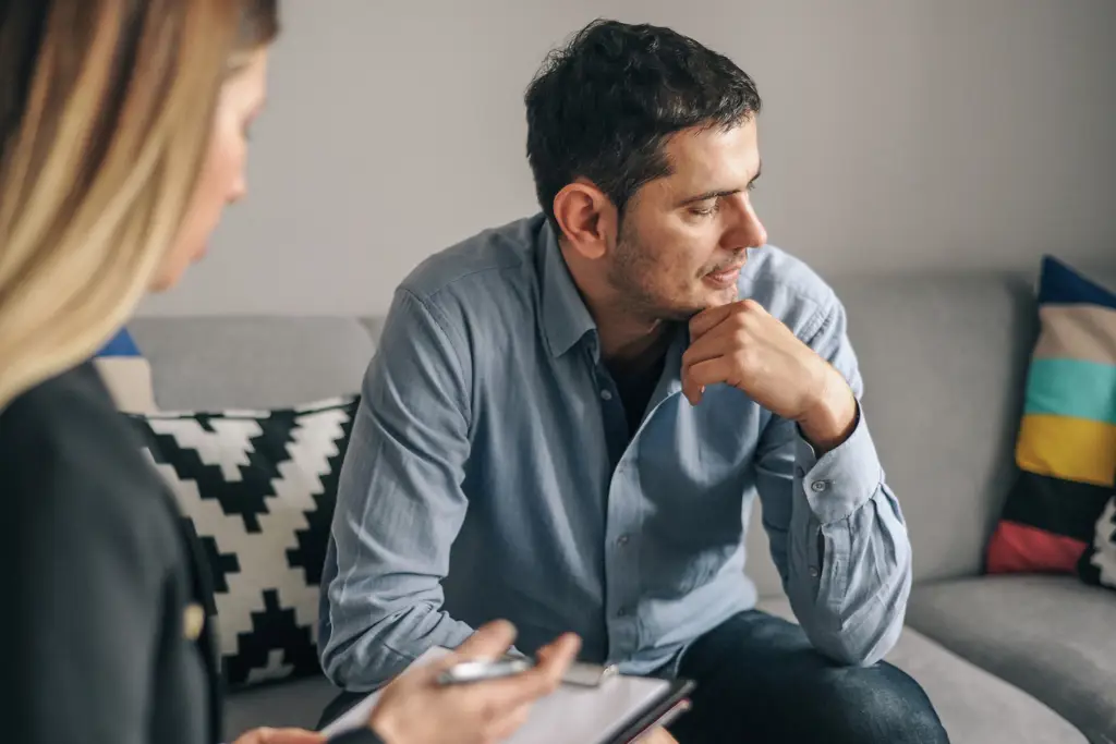 A woman taking notes and a man sitting on a couch