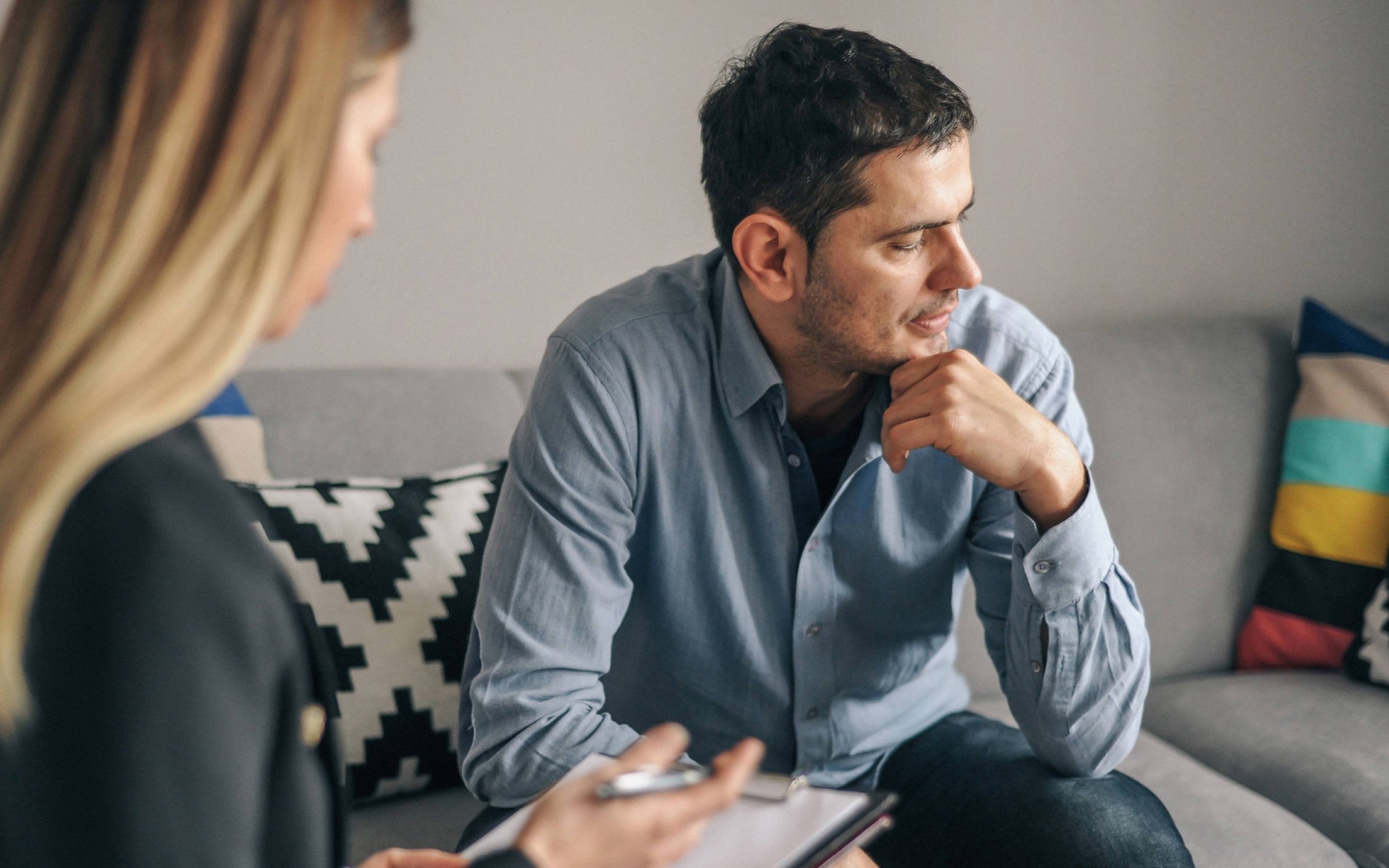 A woman taking notes and a man sitting on a couch