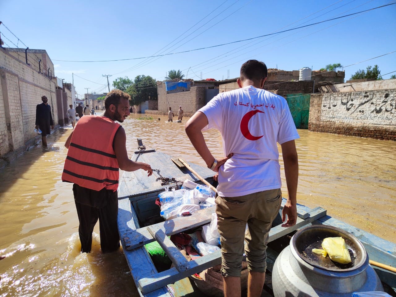  Two men standing in a flooded street with a boat. Photo: Red Cross/Red Crescent