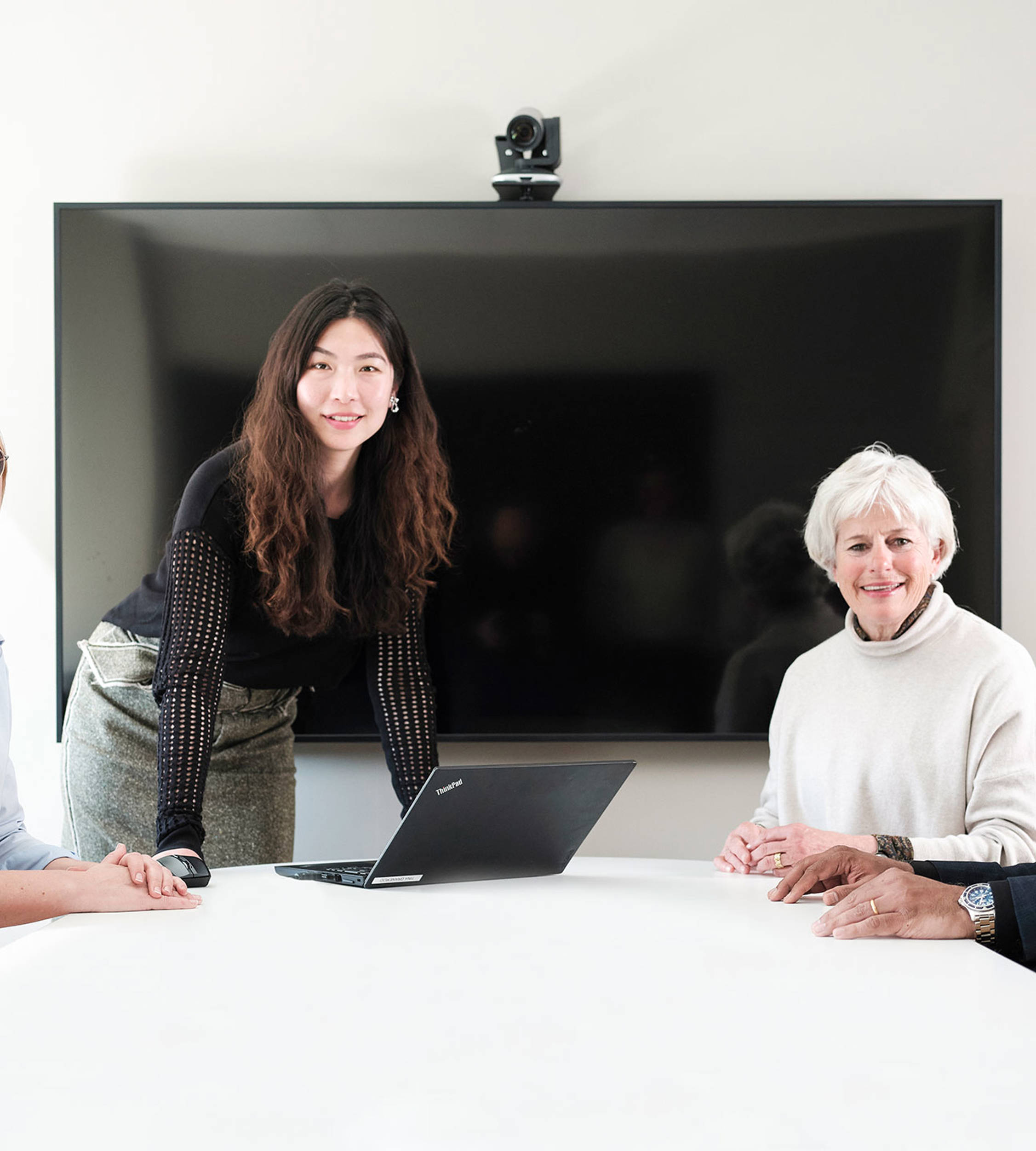 Four people in a meeting room facing the camera