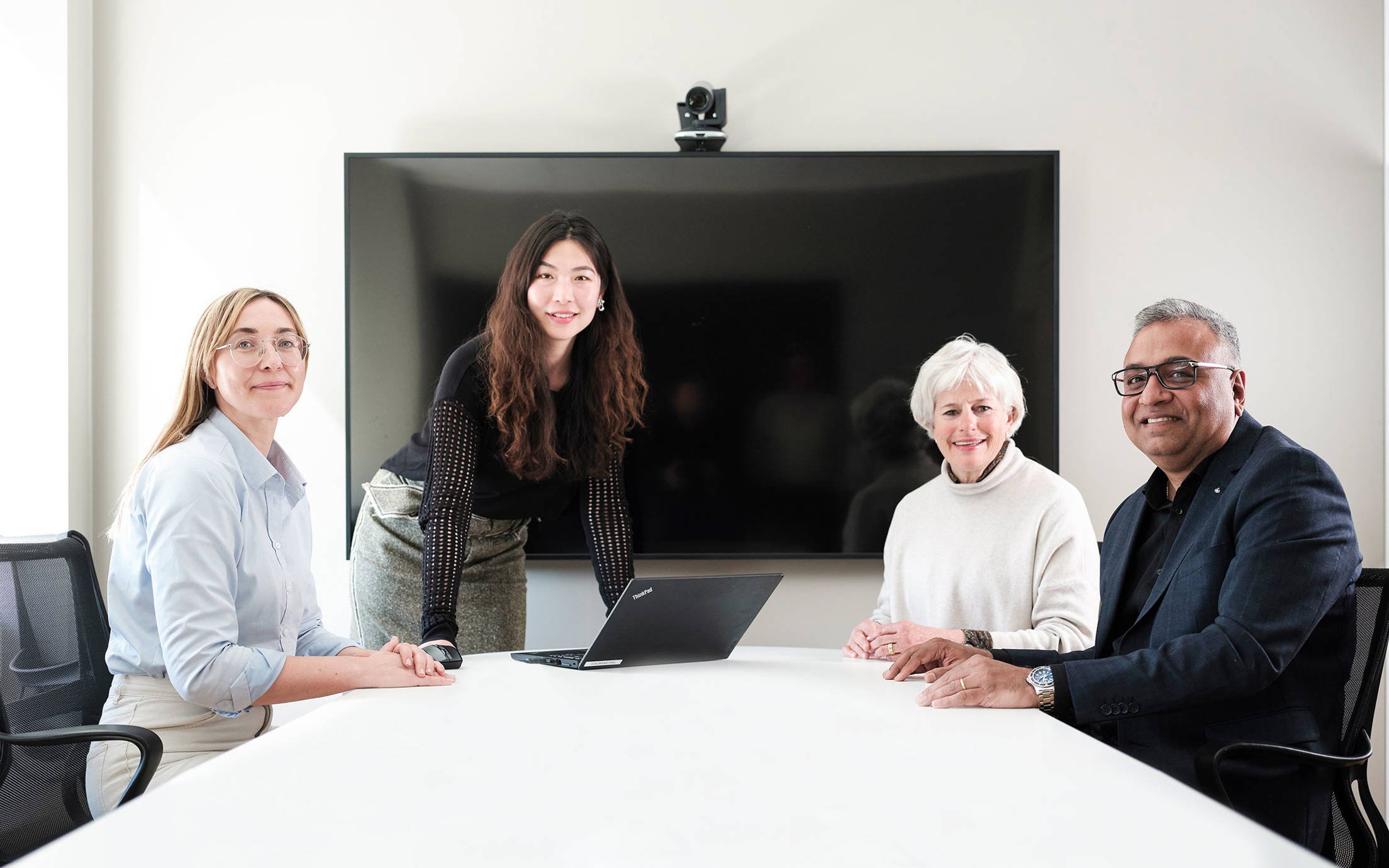 Four people in a meeting room facing the camera