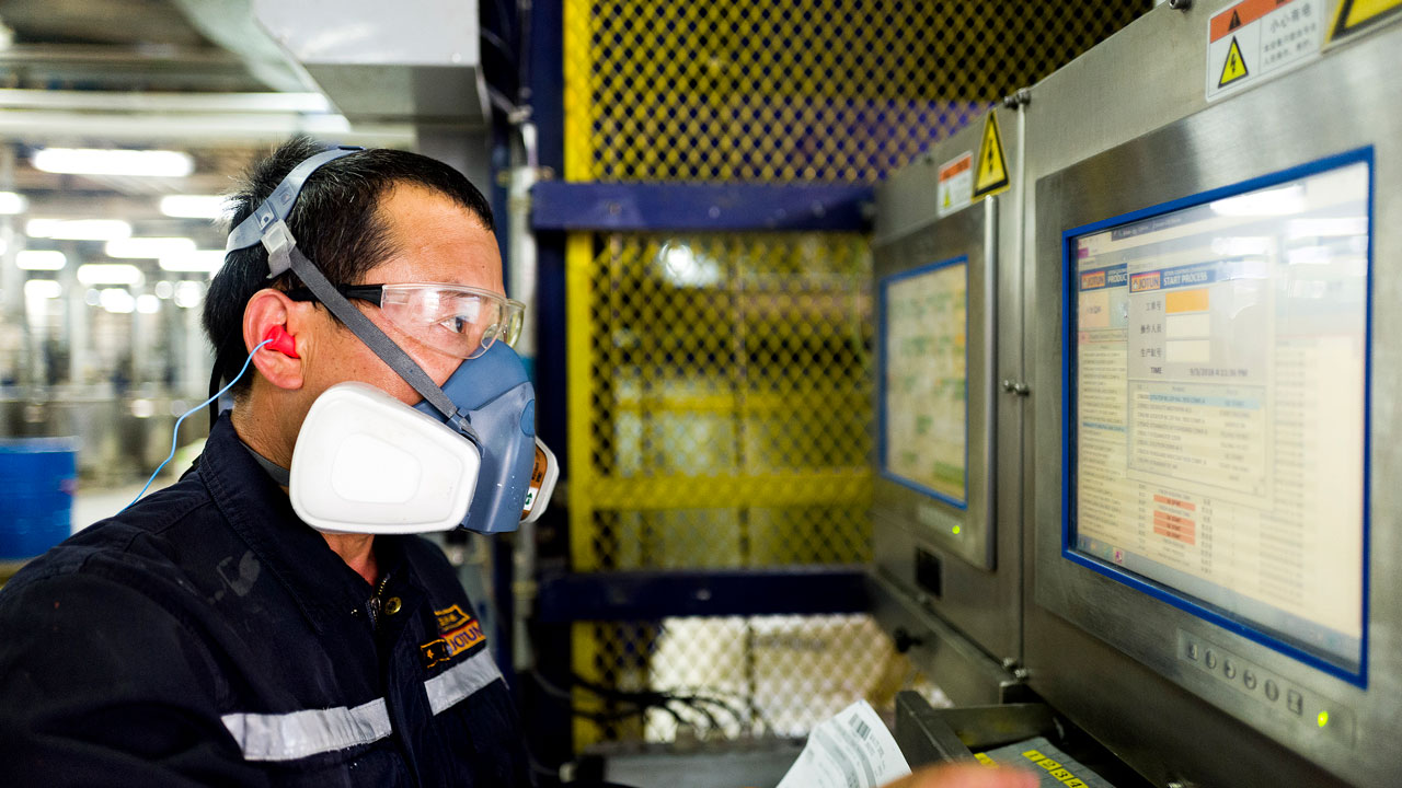 A factory worker wearing protective glasses and mask