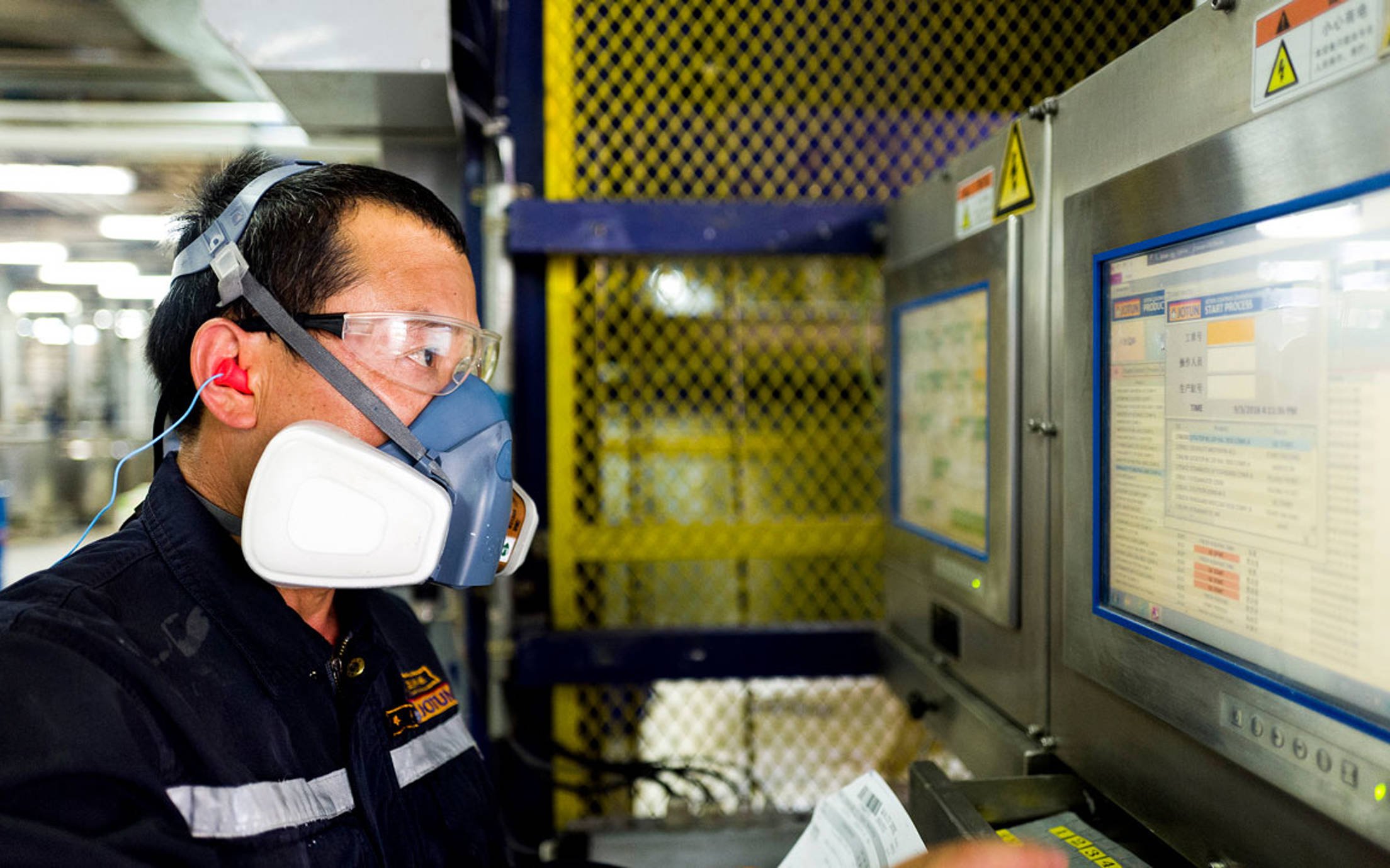 A factory worker wearing protective glasses and mask
