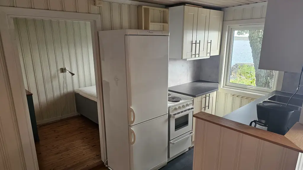 Lite hyttekjøkken med et soverom bakenfor.